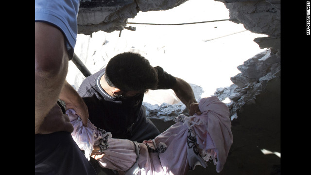 Men carry the covered body of a child killed in an attack by Syrian government forces in Aleppo on Friday.