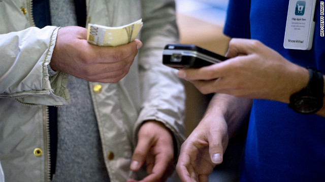 A customer, left, holds euro banknotes to purchase the new phone from an Apple Store employee in France.