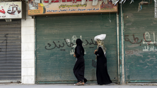 Syrian women walk past closed shops in Aleppo on Friday.