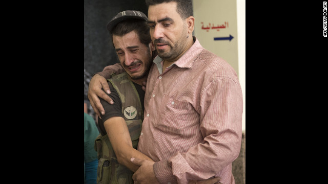 A Syrian rebel is comforted by a friend as he mourns the death of a comrade at a hospital in Aleppo on Friday.