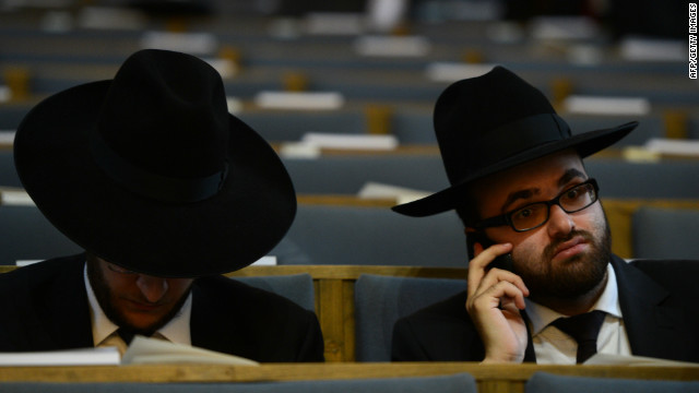 A man uses his phone before a ceremony to ordain four rabbis in a German synagogue. 