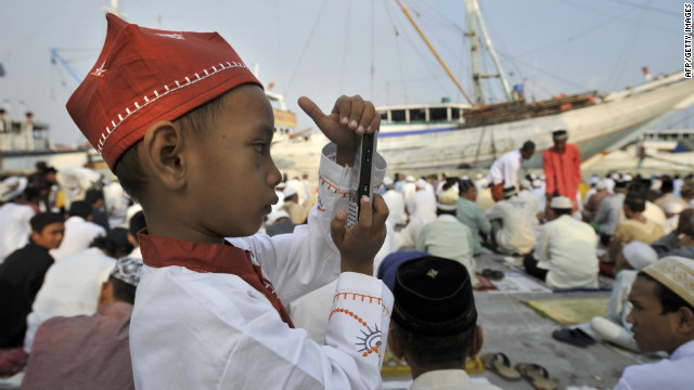 A young Indonesian boy takes a photo with a mobile phone following prayers at the old Jakarta port of Sunda Kelapa where he was celebrating the three-day Eid al-Fitr festival. 