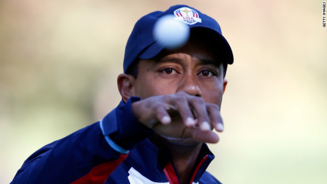 Team U.S.'s Tiger Woods reaches for a golf ball on the practice ground on Thursday.