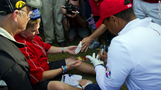 Tiger Woods signs his glove for a fan who was struck in the head during his drive off the seveth tee on Friday.