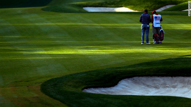 Webb Simpson of the USA waits in the fifth fairway with his caddie Paul Tesori.