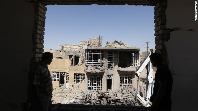 Residents look on as they stand at the site of a bomb blast in the town of Taji, north of Baghdad, Sunday.