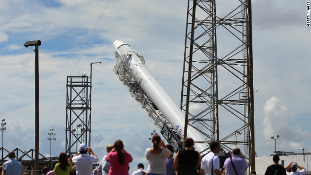 People watch as the SpaceX Falcon 9 rocket and its unmanned Dragon capsule are readied for launch Sunday in Cape Canaveral, Florida.