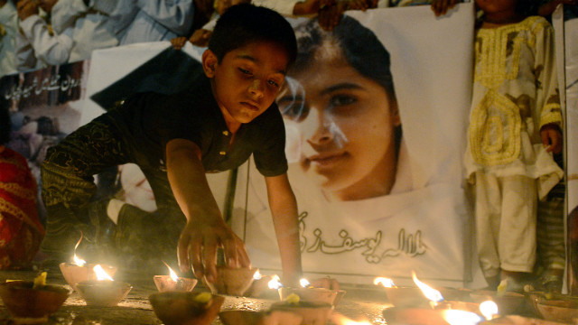 A Pakistani youth places an oil lamp next to a photograph of Malala on Friday in Karachi.