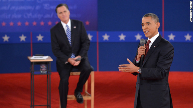 President Obama promotes his policies as Mitt Romney listens.