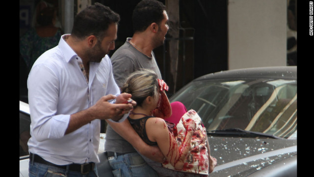Lebanese men evacuate a wounded woman from the scene of the car bomb.
