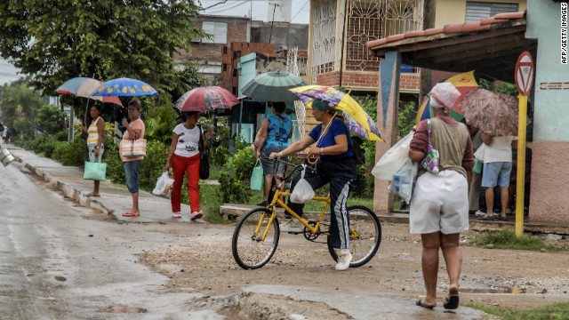 People in Bayamo hold umbrellas as they purchase food Wednesday before the arrival of the hurricane.