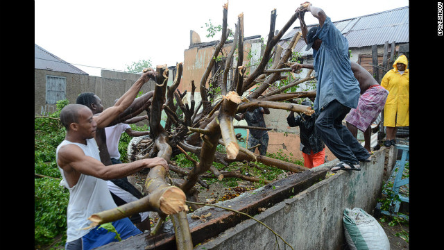 Men deal with downed tree branches after heavy rain caused by Hurricane Sandy in Kingston, Jamaica, on Wednesday, October 24.