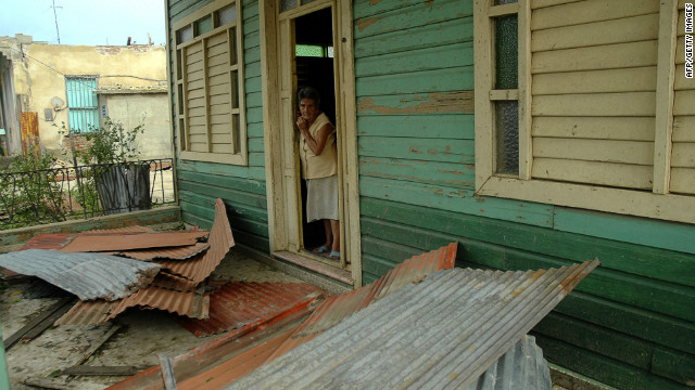 A woman peers out the door of her house Thursday after it was damaged by Hurricane Sandy in Bayamo, Cuba.