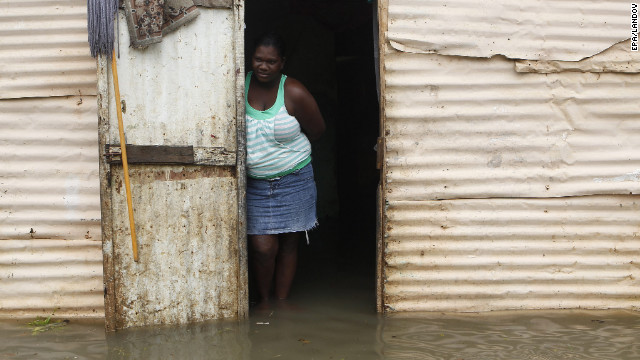 A woman stands at the entrance of her house surrounded by flood water after heavy rains in Santo Domingo, Dominican Republic, on Thursday.