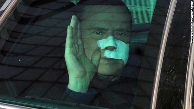 Berlusconi waves to journalists as he leaves San Raffaele hospital in Milan on December 17, 2009. Berlusconi suffered severe facial wounds in a violent attack.