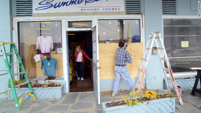 Bob Kaege takes a measurement while boarding up a shop in Cold Spring, New Jersey, on Saturday as Marie Jadick speaks on the telephone getting an updated weather report in preparation for Hurricane Sandy.