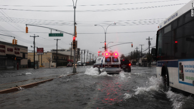 An ambulance maneuvers through water on Rockaway Beach Boulevard in Queens as the weather sours Monday in New York City.