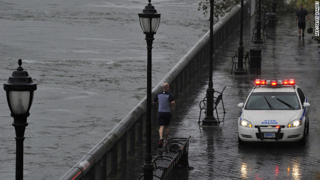 A jogger runs along the East River in New York on Monday as a police car secures the area.