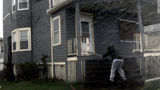  A woman examines her storm-damaged porch as heavy rain continues to pour in Winthrop, Massachusetts, on Monday.