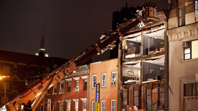 Firefighters evaluate an apartment building in New York that had the front wall collapse during the storm on Monday.