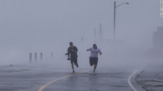 Two men run down Foster Avenue while dodging high winds and waves from the storm on Monday in Marshfield, Massachusetts.
