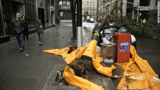 Passers-by look at a car that was crushed by a tree near New York's financial district on Tuesday.