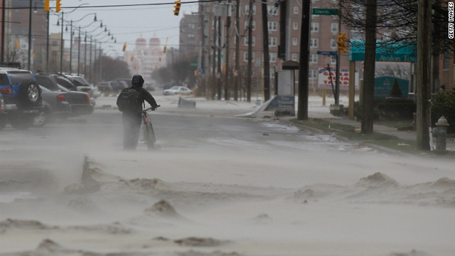 A resident walks down a street covered in beach sand due to flooding from Hurricane Sandy in Long Beach, New York on Tuesday.