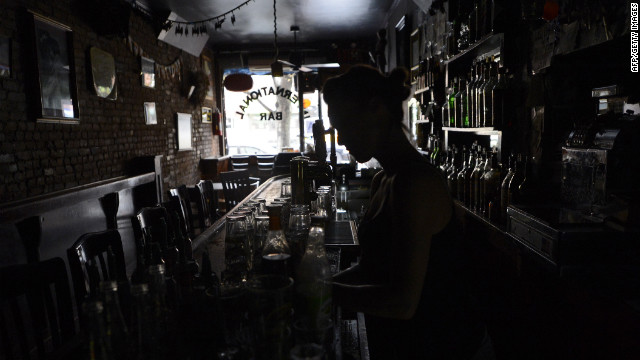 A bartender at the International Bar in the East Village neighborhood of New York City makes drinks in the dark on Tuesday as electricity remains out for many in the city.