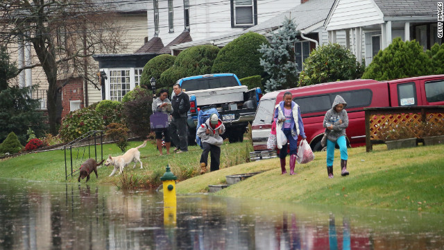 Kira Brizill leads family members as high tide and winds flood the street on Monday in Freeport, New York.