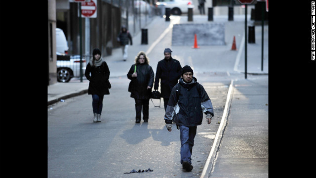 People walk to work Wednesday on a normally busy street near the New York Stock Exchange.