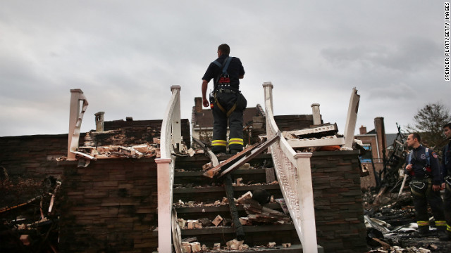 A firefighter stands on the porch of a home destroyed by fire in Queens on Wednesday.