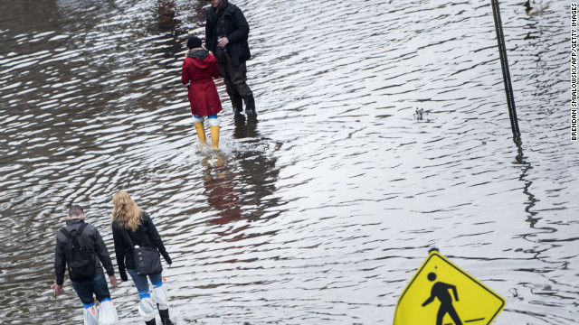 People walk down a flooded street on Wednesday, October 31, in Hoboken, New Jersey. 