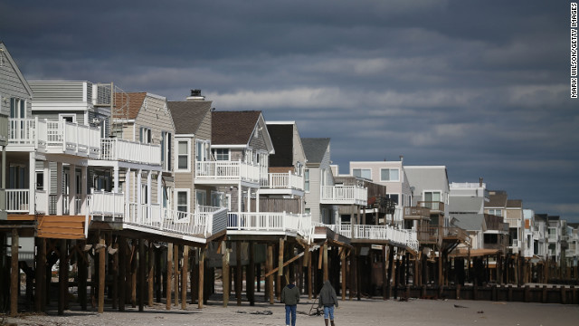 People walk past homes damaged by Hurricane Sandy in Long Beach Island, New Jersey.