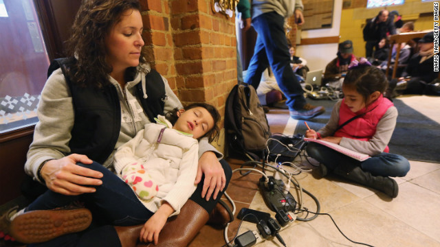 Bridget De La Torre holds her daughter Neve, 3, as daughter Paz sits nearby while they rest and charge devices on Thursday. They were at a shelter for those affected by Superstorm Sandy at Saints Peter and Paul Church in Hoboken, New Jersey. Bridget's family has no electricity or hot water, and their car was destroyed by flooding. 