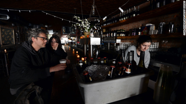 Matthew Mark Meyer, left, and Annie Barwick, center, sit in a darkened Randolf Beer Restaurant which is using generator power to reopen on Friday in New York City.