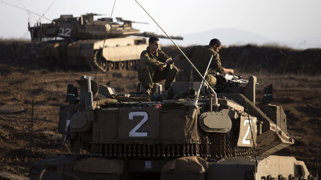 An Israeli Merkava tank crew sits in the Israeli-controlled Golan Heights overlooking the Syrian village of Breqa on Tuesday, November 6. An Israeli military vehicle in the Golan Heights was hit by gunfire from Syria on Monday, the Israeli army said. 