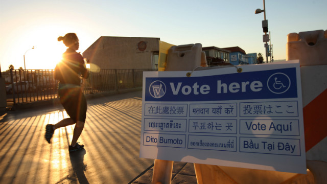 A jogger on The Strand in the Los Angeles area community of Hermosa Beach passes a directional sign to a polling place at sunrise.
