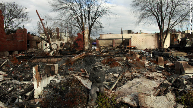 A statue of a firefighter stands in front of a burned down house Sunday in Rockaway, New York.