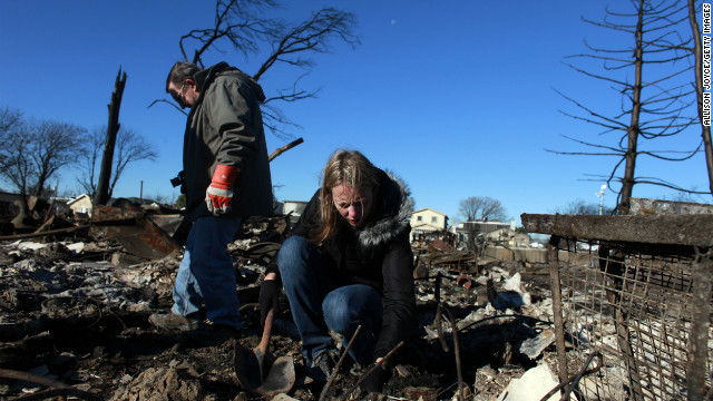 People sift through their damaged home on Sunday in Breezy Point.