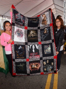 Two fans hold up a "Twilight" quilt.