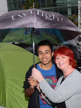 Two fans brave the rain with a "Twilight" umbrella at tent city.