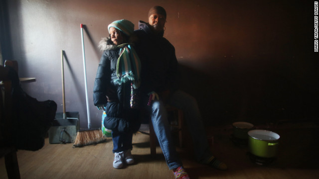 Mac Baker, right, poses with her niece Nytaisha Baker next to pots of water she heats on the floor with small flames for a bit of warmth in Baker's unheated apartment in the Ocean Bay public housing projects in the Far Rockaway neighborhood in Queens on Friday, November 9.