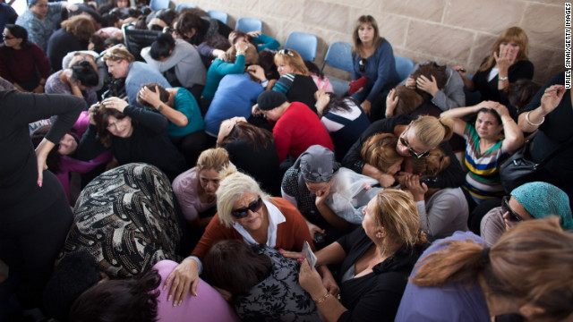People take cover during a rocket attack at a funeral Friday, November 16, in Kiryat Malakhi, Israel.
