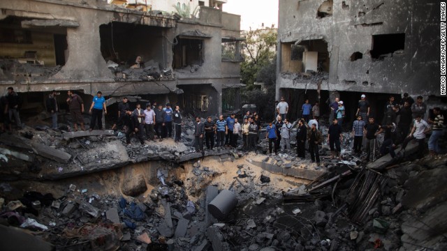 Palestinian men gather around a crater caused by an Israeli airstrike at a home in Gaza City on Sunday, November 18.