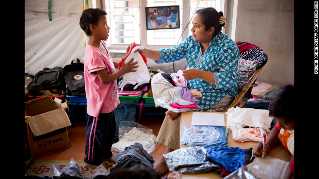 Basnet hands out new clothes to one of the young children she cares for in Kathmandu. The children reciprocate her love by calling her "Mamu," which means "mommy."