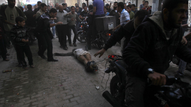 Men on motorcycles drag the body of man through the streets of Gaza City on Tuesday. The men dragging the body claimed it was the body of a collaborator and an Israeli spy.