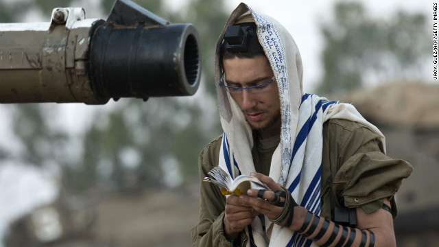 An Israeli soldier reads his morning prayers Tuesday at an Israeli army deployment area near the Israel-Gaza border as they prepare for a potential ground operation in the Palestinian coastal enclave. 