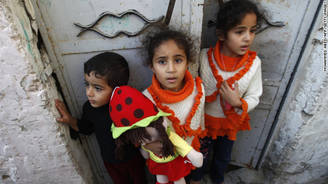 Palestinian children stand at the gate of their home Tuesday as they watch a funeral procession for those killed following an Israeli airstrike in northern Gaza. 