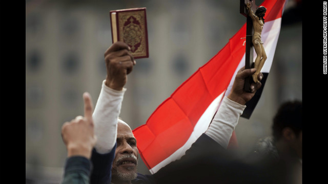 An Egyptian protester holds up a Quran and a figure of Christ on the cross during Tuesday's demonstration.