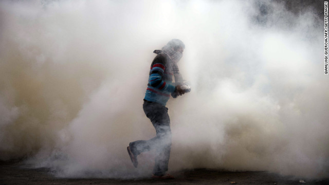 An Egyptian protester attempts to throw back a tear gas canister on Tuesday during clashes with riot police in Omar Makram Street, off Tahrir Square.